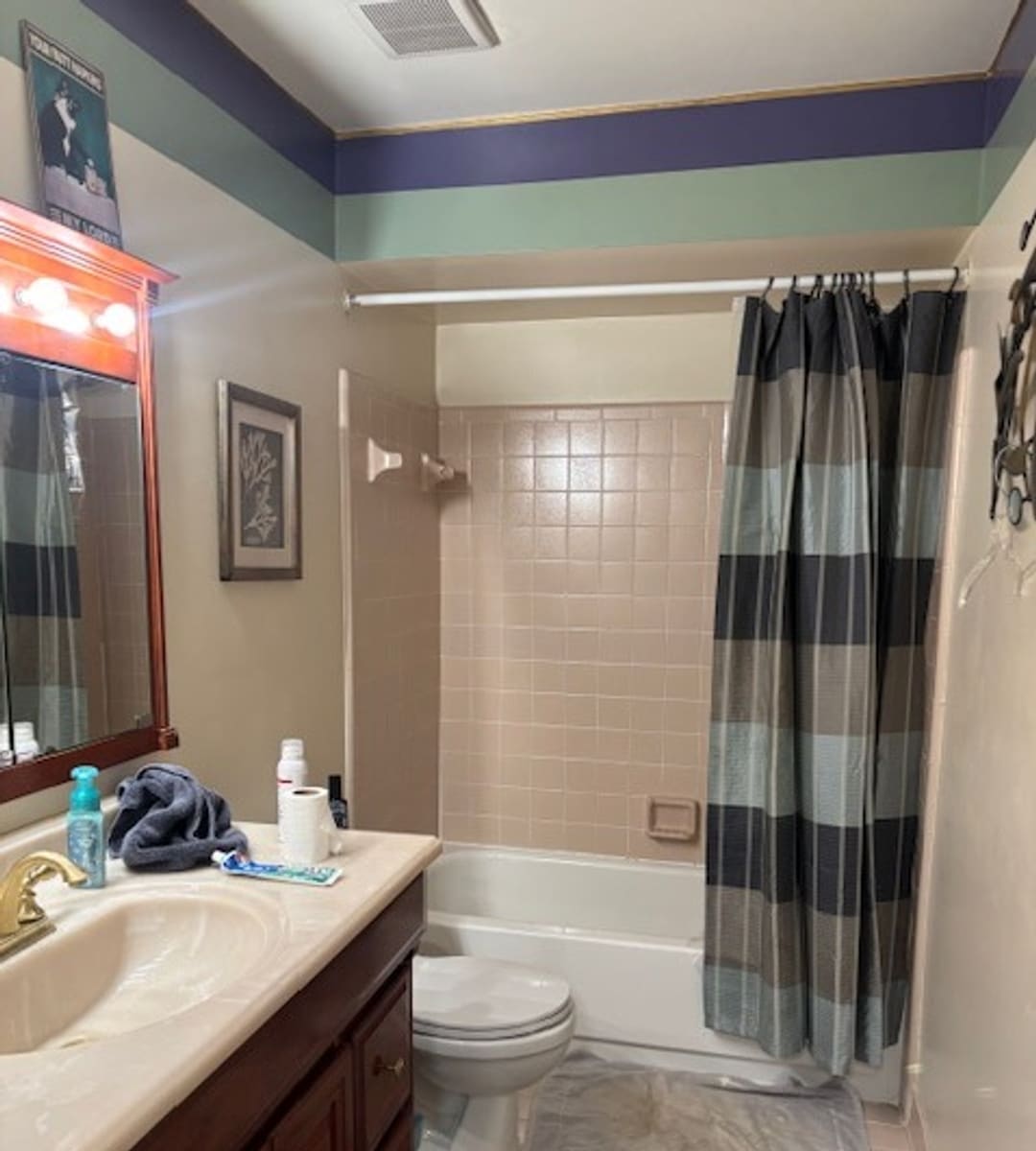 Before: pink tile tub surround with a shower curtain in a Livonia bathroom